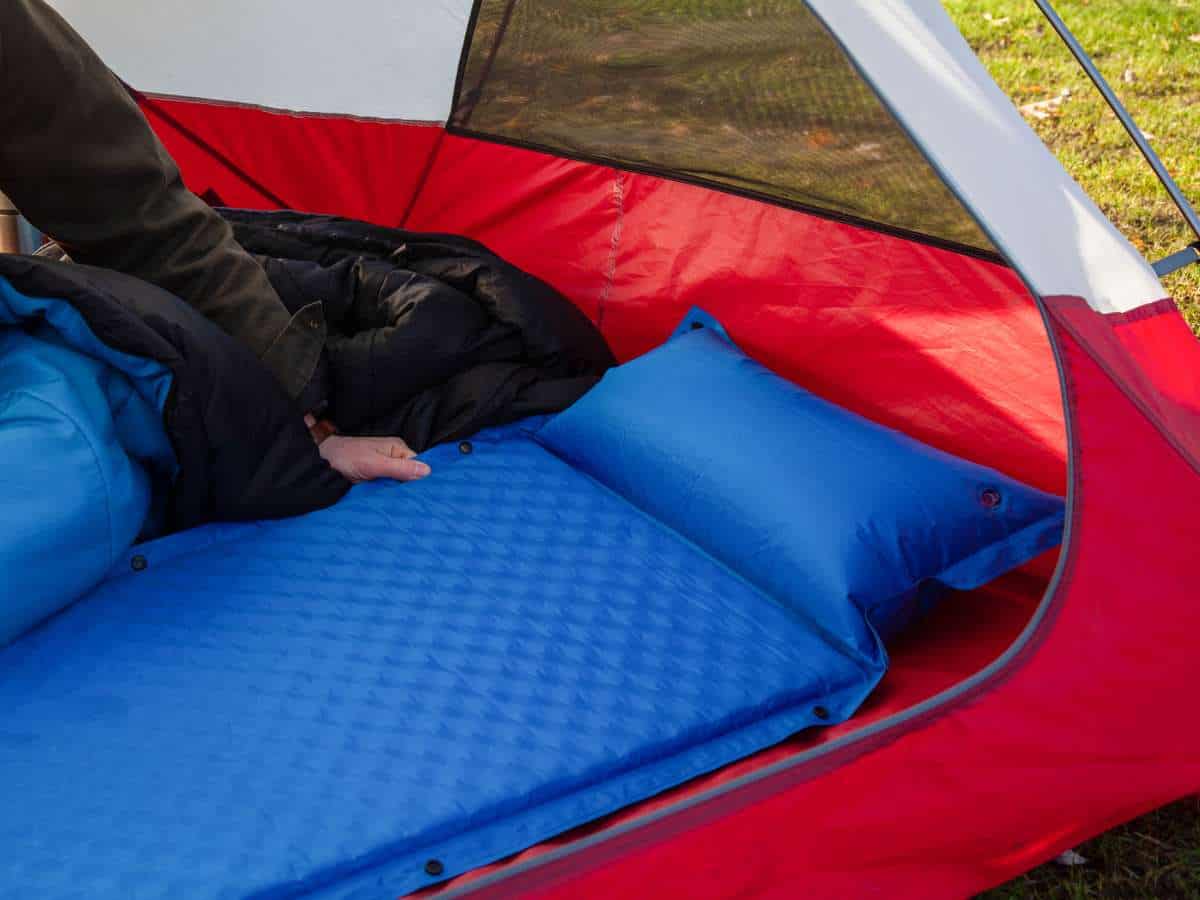 a man laying down a camping mattress