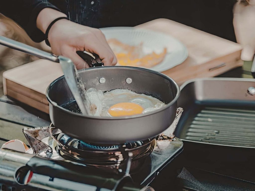 Frying food on a camping stove, highlighting how small camping mistakes with food and planning can quickly become frustrating.