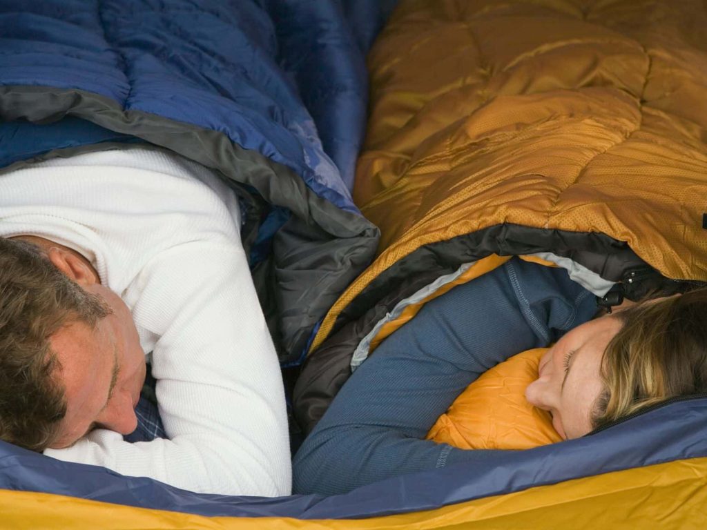 Campers sleeping in sleeping bags, highlighting common camping mistakes like poor insulation or incorrect sleep setup.