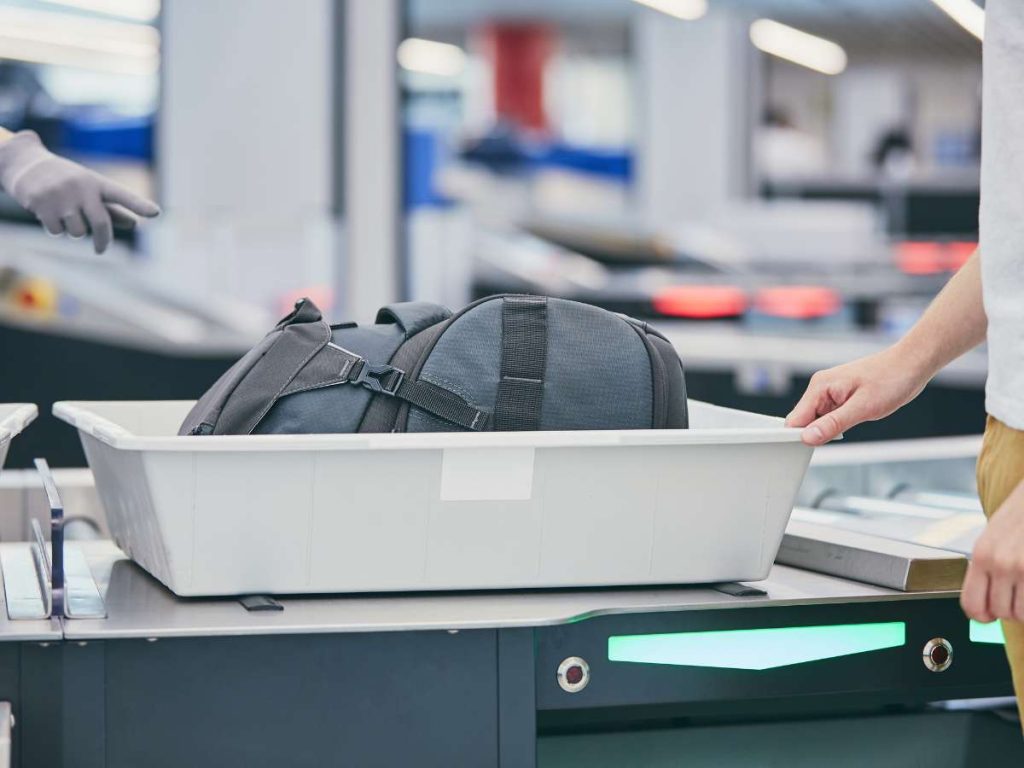Camping gear backpack at airport security screening illustrating flying with camping gear and security checks.