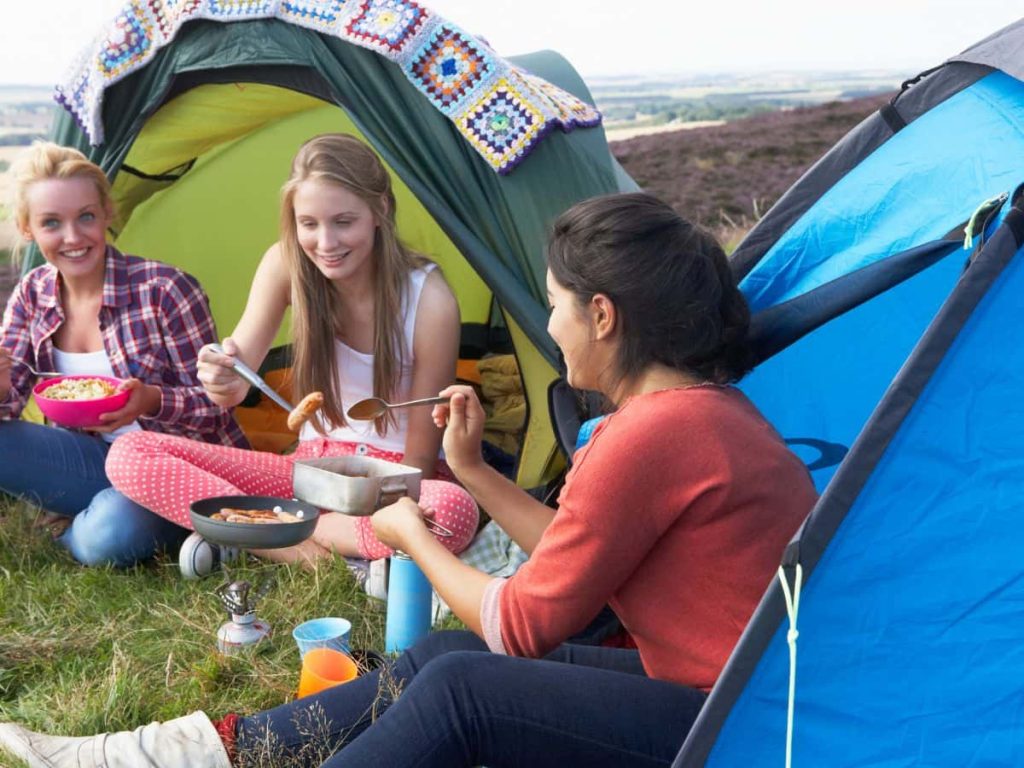 Group cooking at a campsite, showing how camping with teenagers can balance social time and independence