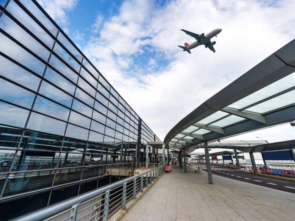 Airplane flying over airport terminal building, representing air travel and flying with camping gear.