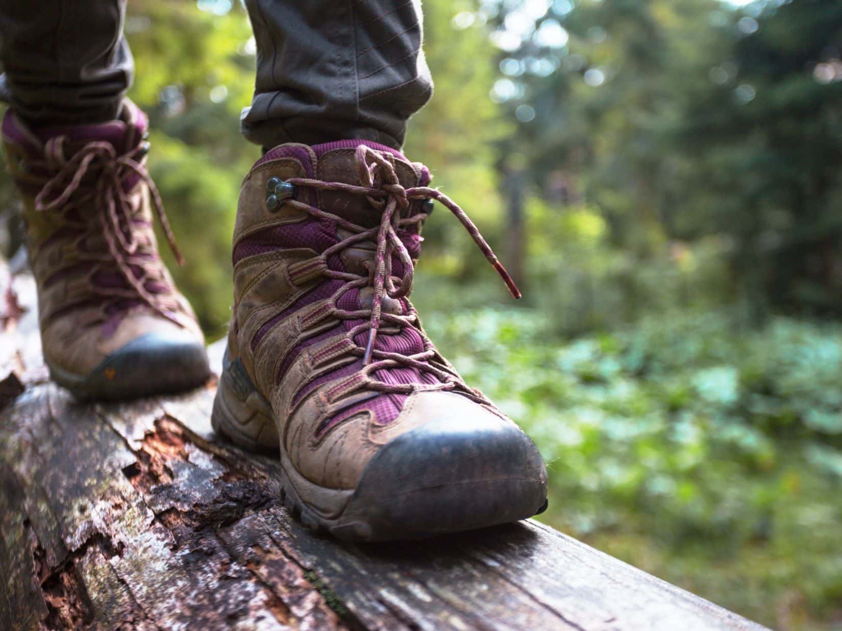 Hiking boots on a log showing common mistakes that cause heel pain in hiking boots.