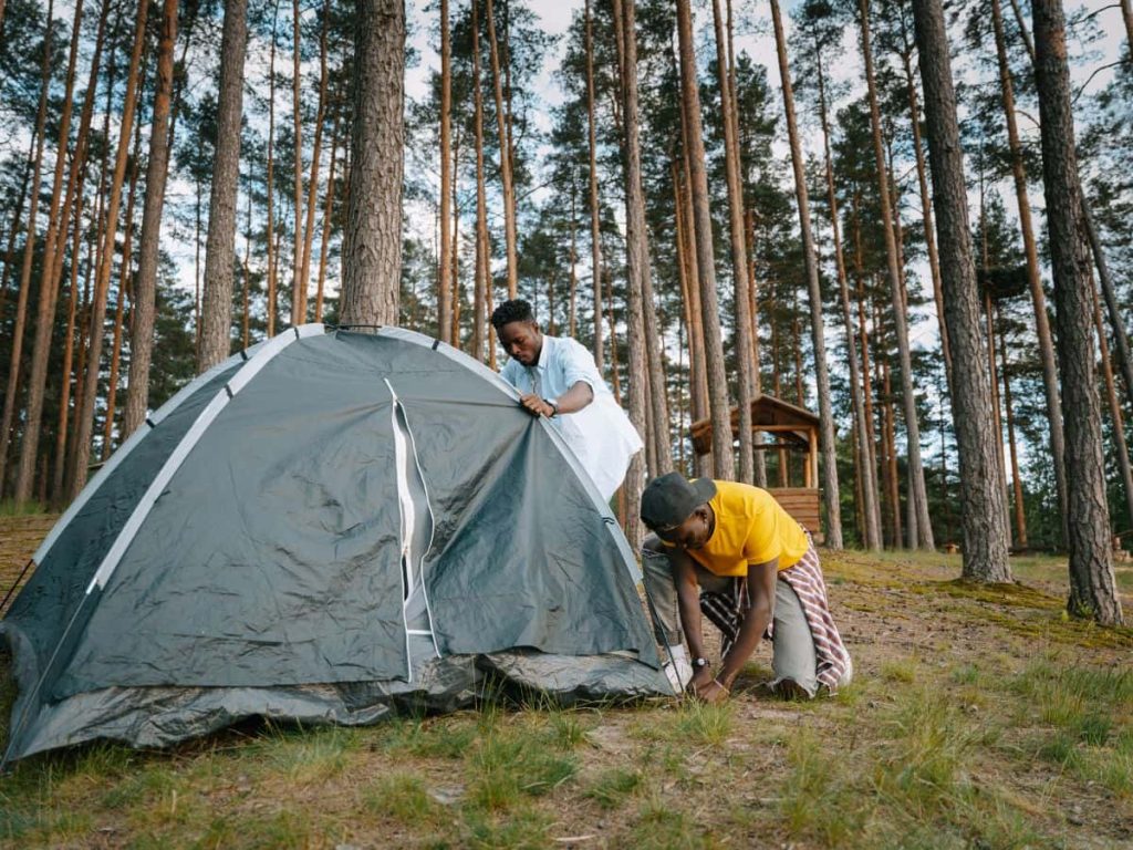 Group pitching a tent outdoors, showing teamwork when camping with teenagers