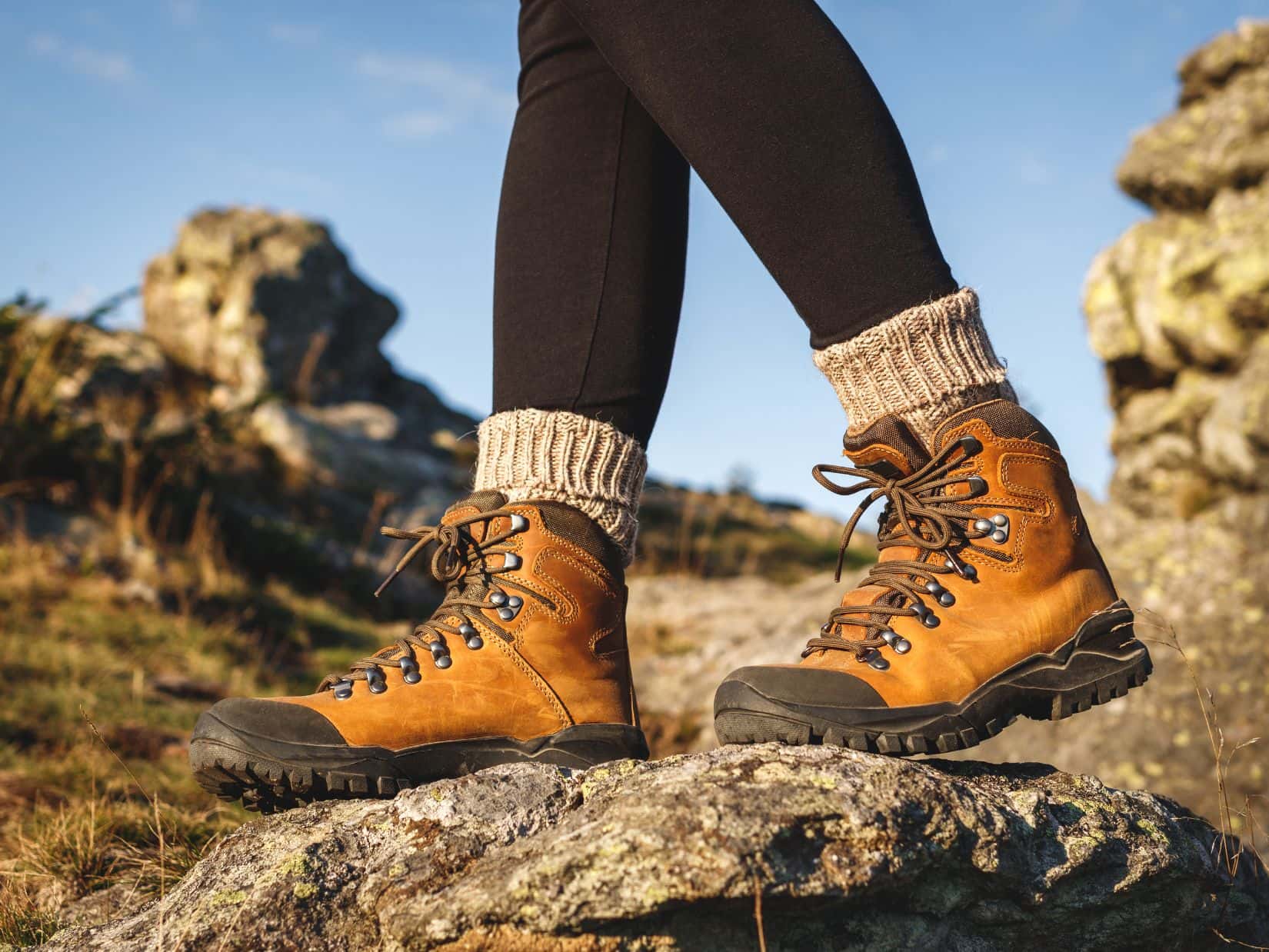 Hiking boots on rocky terrain showing a common cause of heel pain in hiking boots.