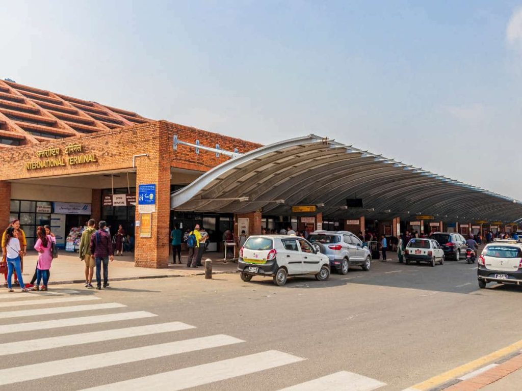 International airport terminal with travellers arriving, illustrating differences when flying with camping gear internationally.