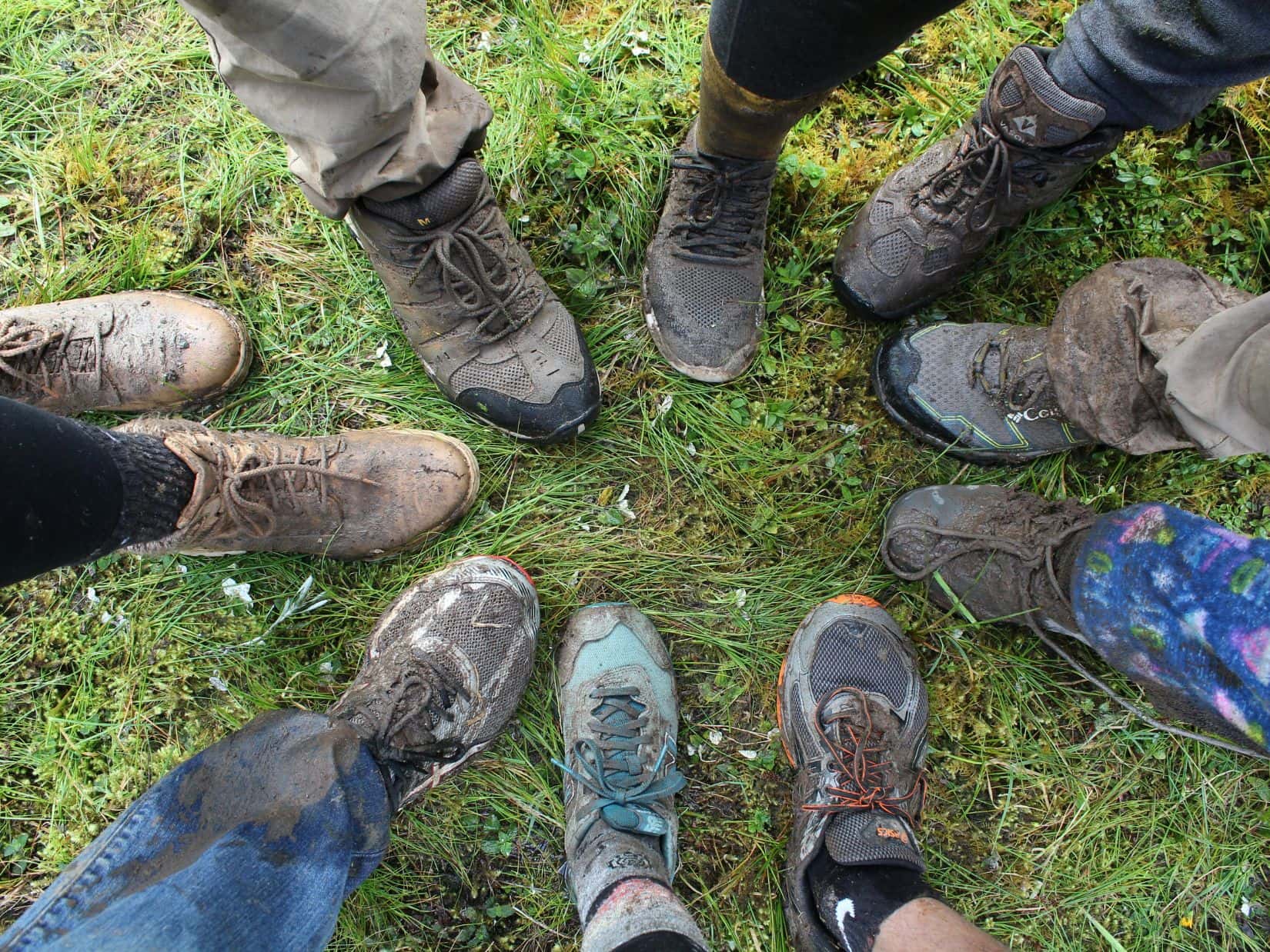 Muddy hiking boots on a trail showing common causes of heel pain in hiking boots.