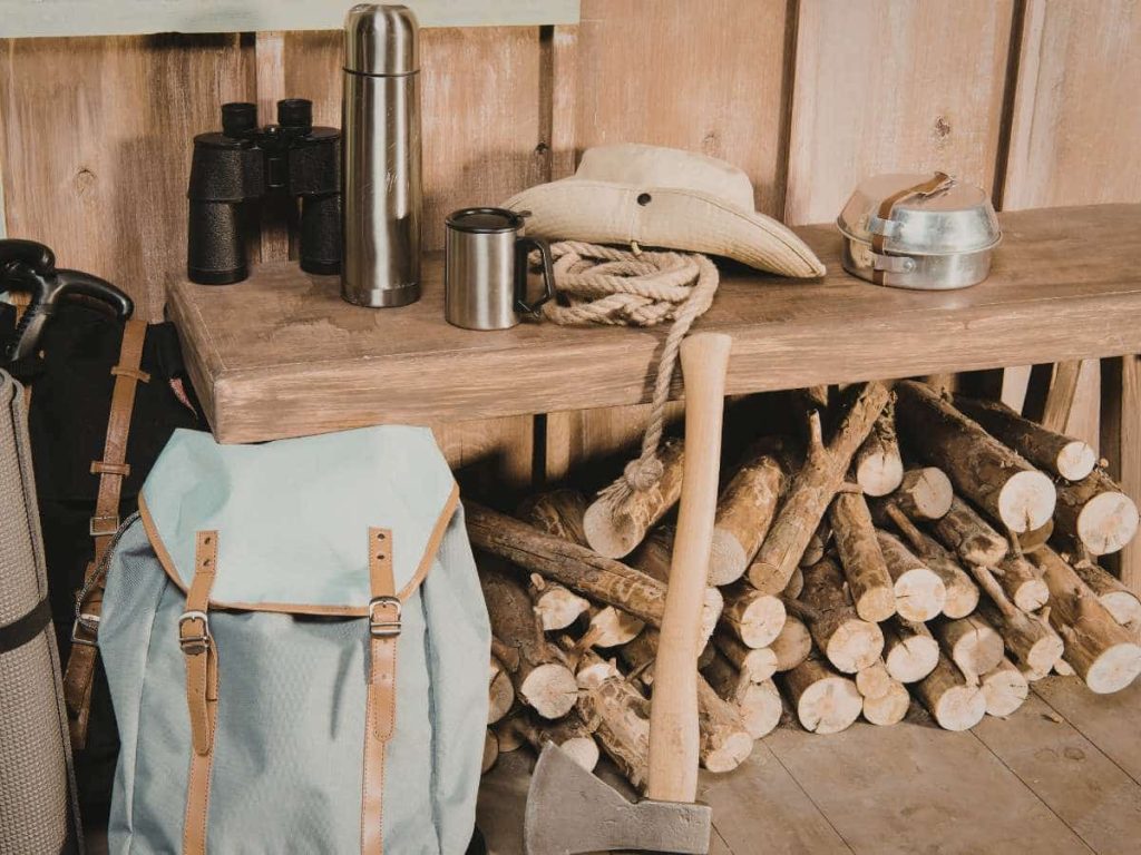 Camping equipment like axe, stove and backpack illustrating what you can and can’t bring on a plane with camping gear.