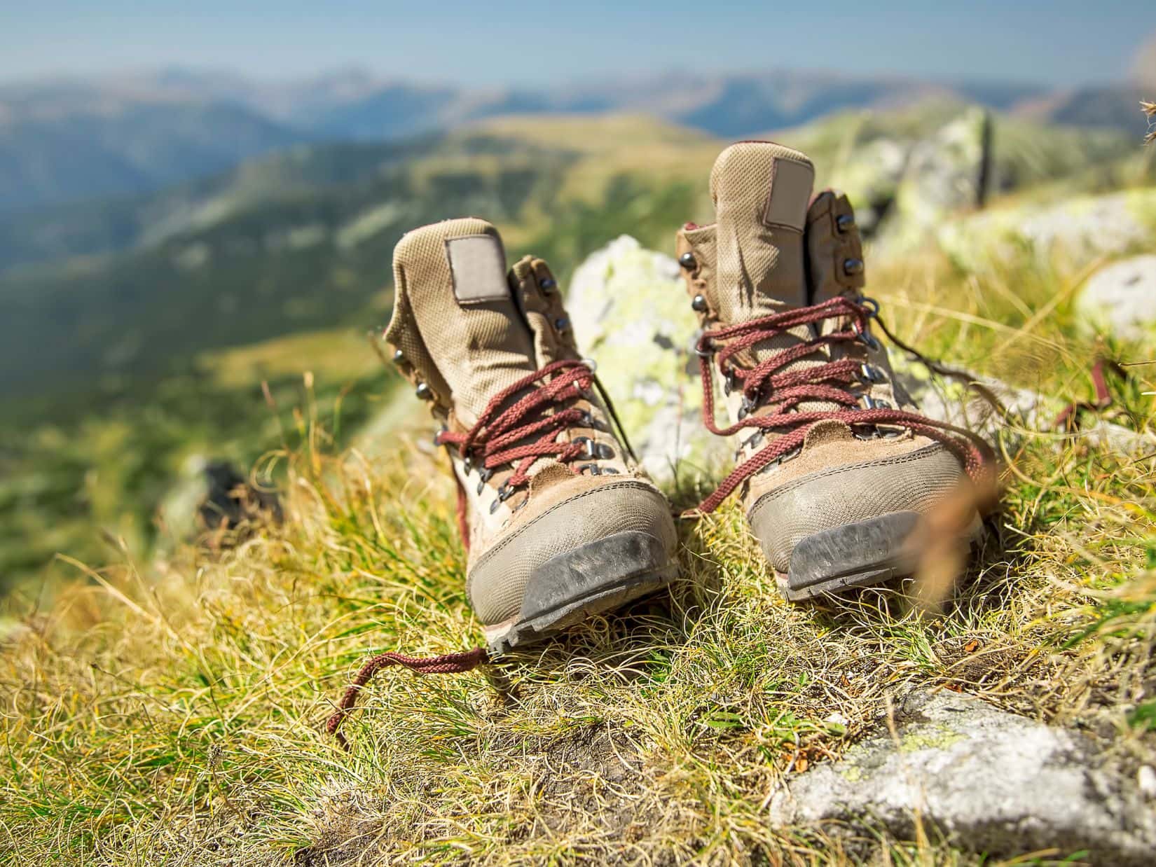 Worn hiking boots on a mountain trail showing when heel pain in hiking boots means it’s time for new boots.