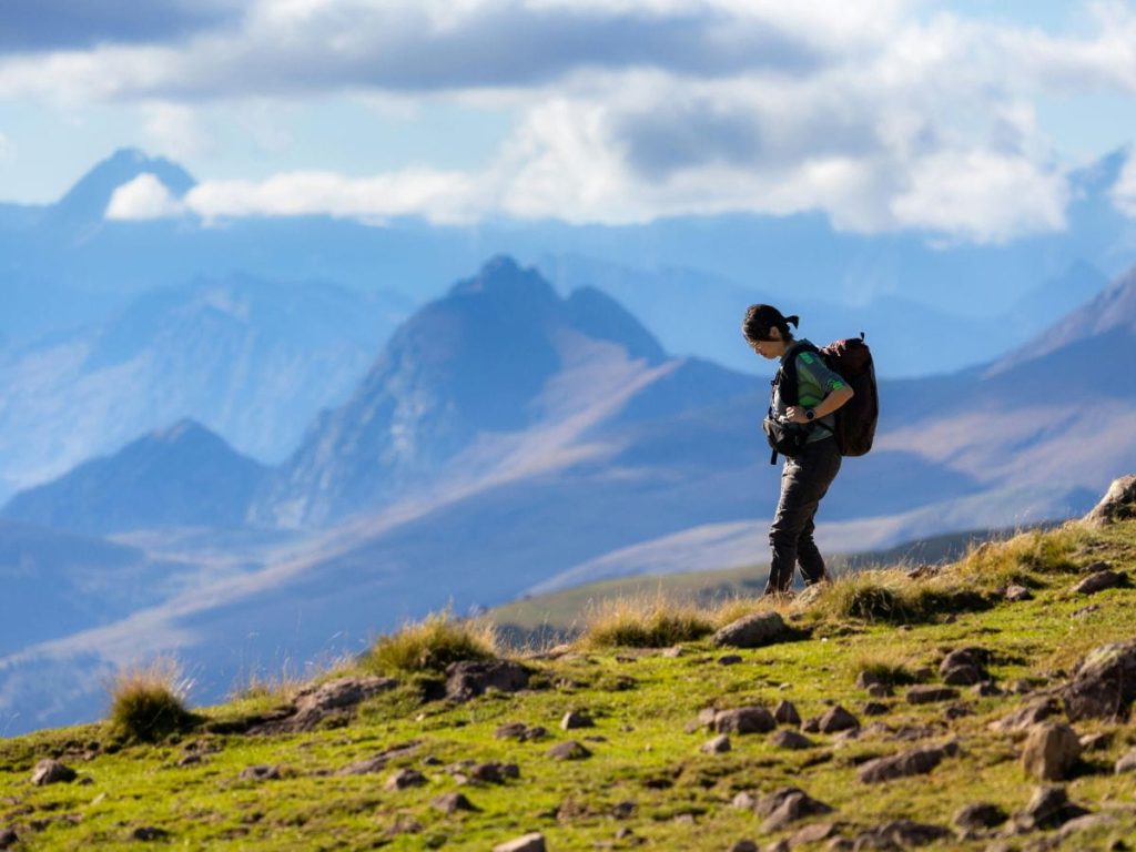Hiker walking in the mountains, showing why comfort and fit matter in hiking boots vs trail runners.