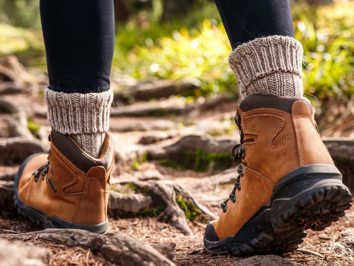 Why do my feet sweat when hiking, shown by thick socks and boots on a forest trail.