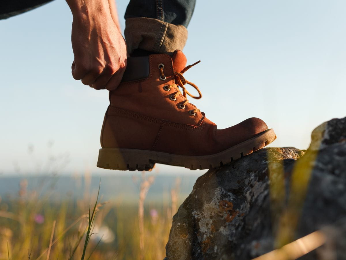 Hiker adjusting their boot before walking to help stop blisters when hiking.