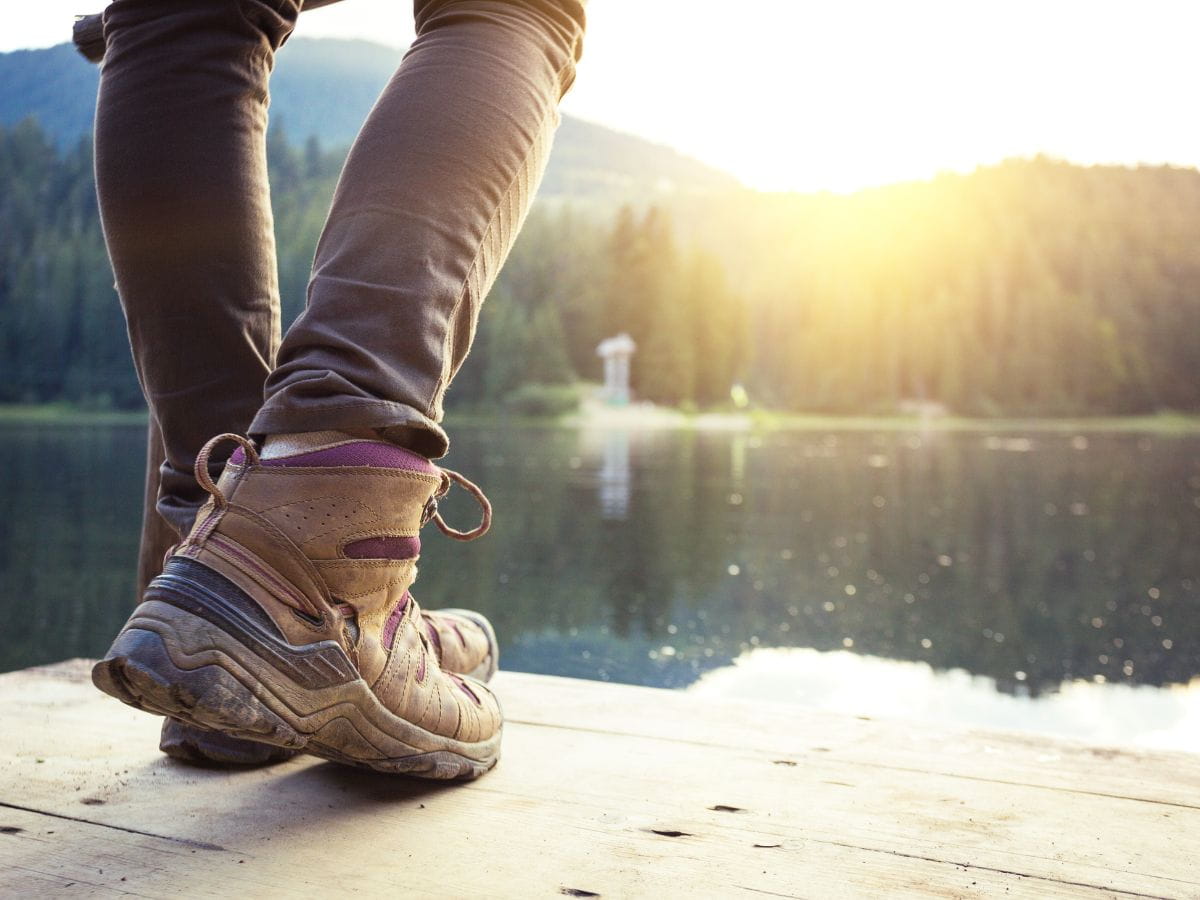 Hiker pausing in walking boots by a lake during a long hike.