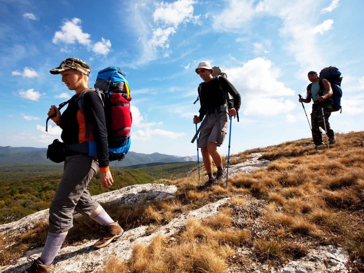 Hikers walking on a rocky trail, showing why blisters happen when hiking.