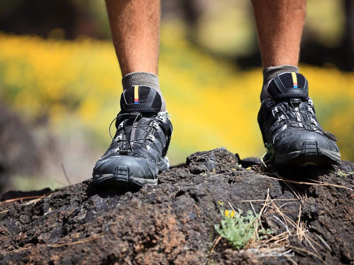 Hiking shoes on rocky ground, showing why your feet sweat more when hiking.