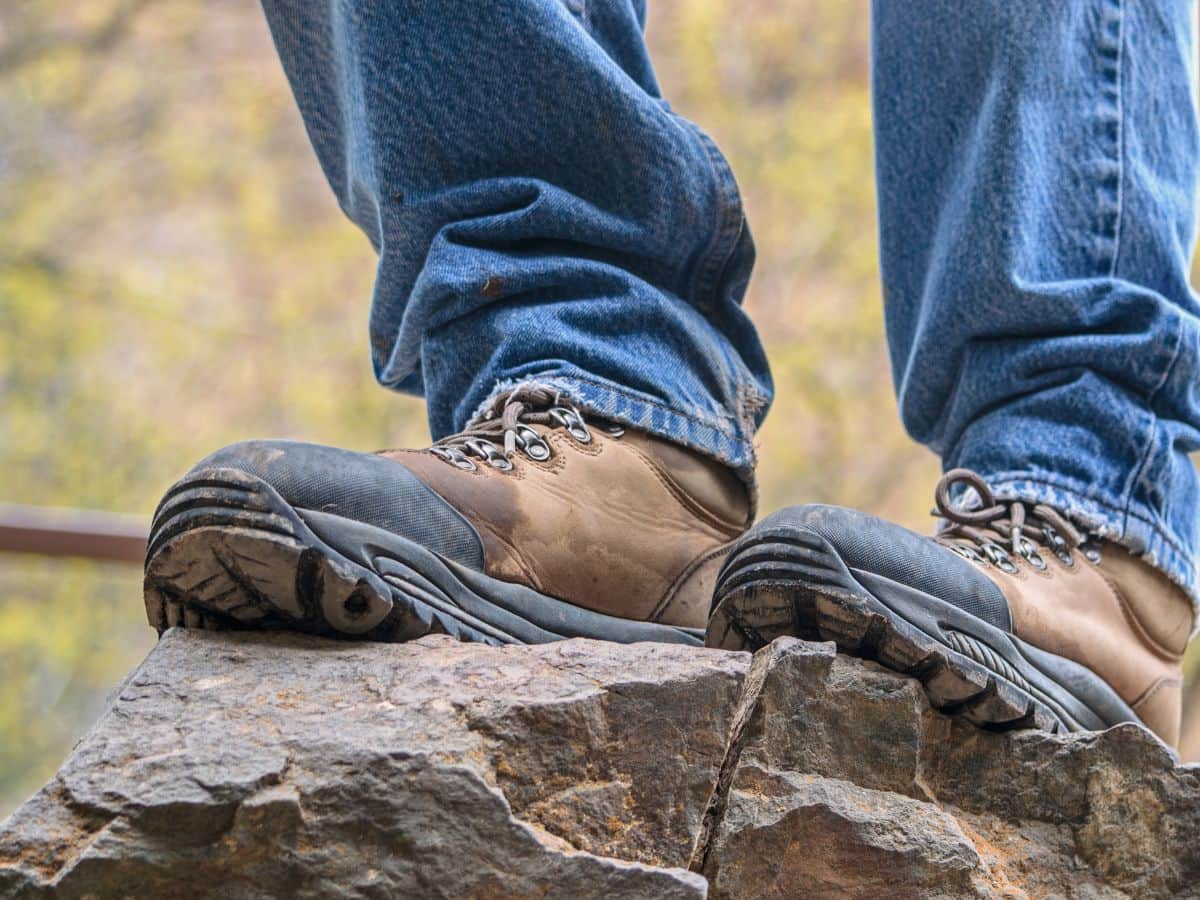 Brown leather hiking boots planted on jagged rocks, testing their comfort, grip and fit before a demanding trail.