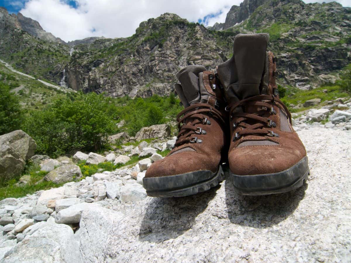 Brown hiking boots on a rugged mountain path, showing why short walks are an important step when learning how to break in hiking boots.