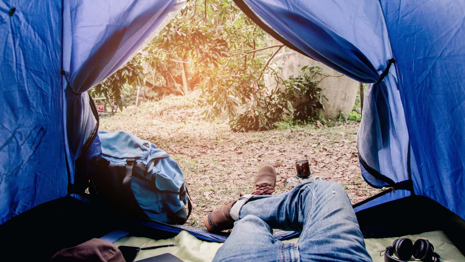 View from inside a tent of a hiker resting with legs stretched out after a day outdoors, illustrating overnight camp recovery for multi-day hiking with lower back pain.