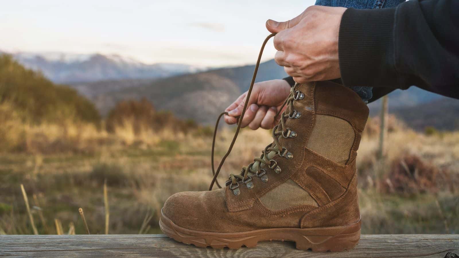 Hiker tightening the laces on a sturdy boot before a hike through deep mud, showing how proper boot lacing and secure footwear can help prevent mud suction from pulling your boots loose.